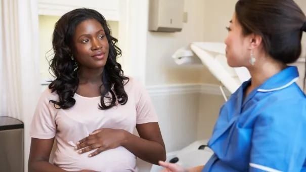 Gravid kvinna samtalar med vårdpersonal i förlossningsmiljö