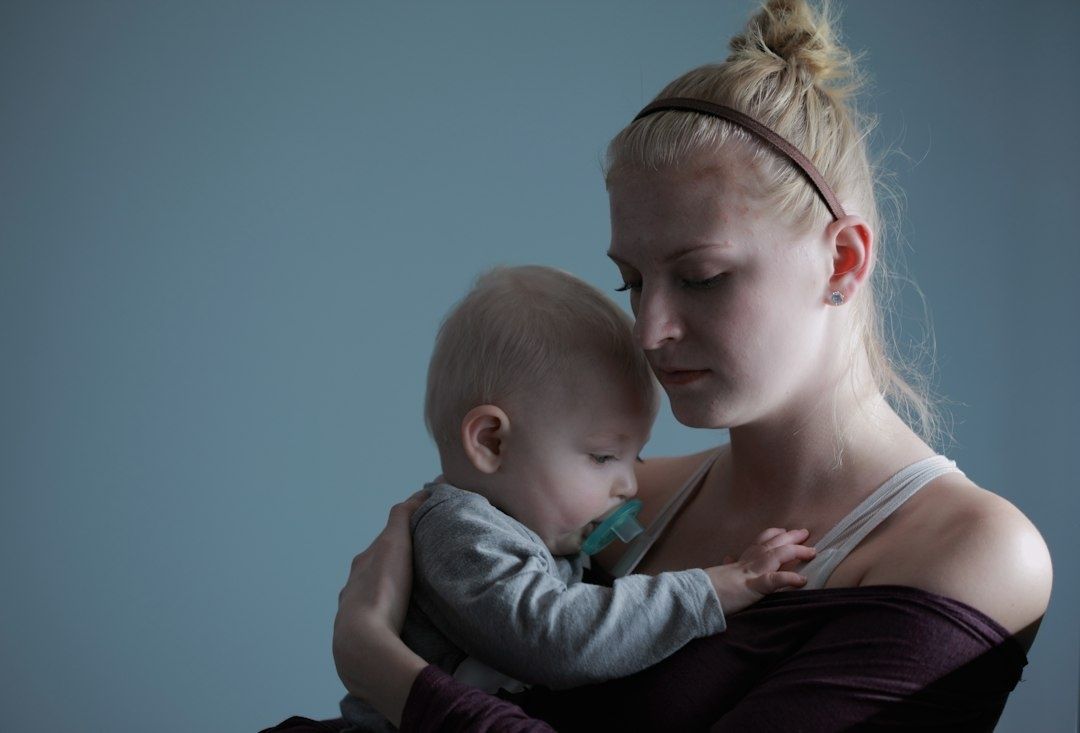 Mamma håller sitt spädbarn nära och ser eftertänksam ut
